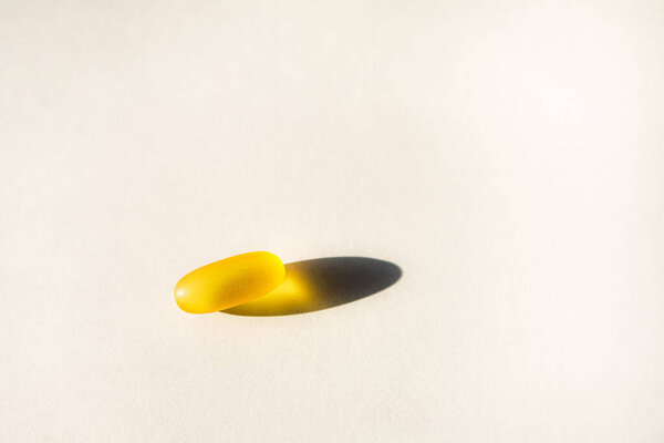 Желтые капсулы с нутрицевтическими веществами в ложке. Таблетки и лекарства.