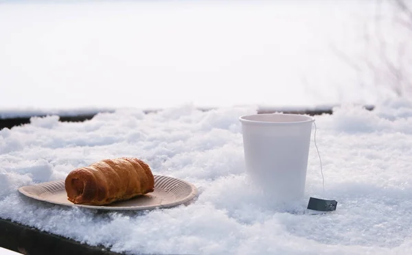 Біла паперова чашка з гарячим чаєм на сніжному столі . — стокове фото