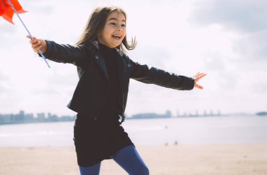 Kırmızı çarkıfelekli mutlu kız dışarıda yürüyor.