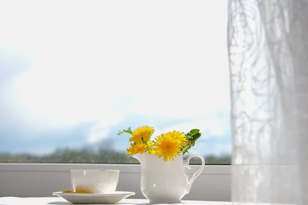 Tasse de thé, fleurs de pissenlit et téléphone. Matin de printemps. Photo De Stock