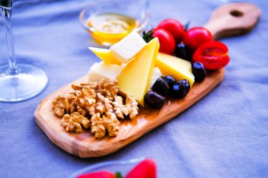 Balkondaki masada iki bardak kırmızı şarap ve peynir tabağı. Evde güzel yemekler..