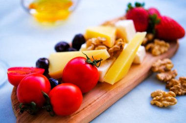 Balkondaki masada iki bardak kırmızı şarap ve peynir tabağı. Evde güzel yemekler..
