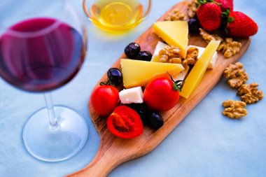 Balkondaki masada iki bardak kırmızı şarap ve peynir tabağı. Evde güzel yemekler..