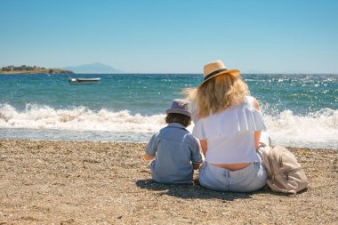 Hasır şapkalı ve kot pantolonlu bir kadının sahile doğru yürüyüşü..