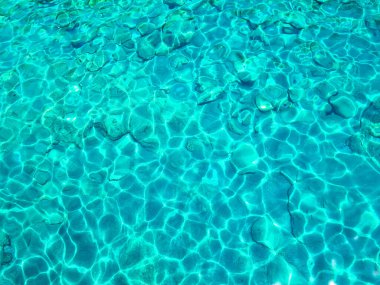 Turquoise surface of transparent sea water with sun glints. Summer vocations background.