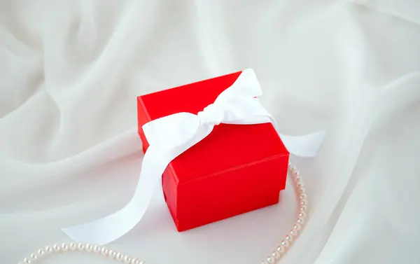 Red Gift Box White Ribbon White Silk Fabric Background Pearl — Stock fotografie