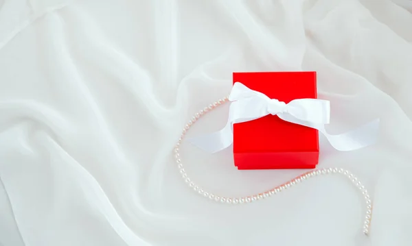 Red Gift Box White Ribbon White Silk Fabric Background Pearl — Stock fotografie