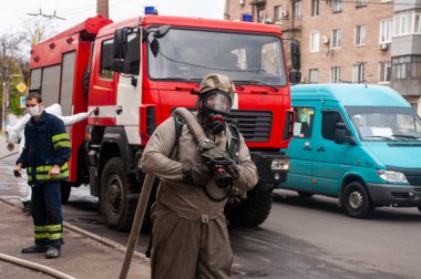 İtfaiyenin kurtarıcısı şehrin sokaklarını dezenfekte ediyor. Koronavirüse karşı önleyici yöntemler. Tehlikeli madde kıyafetleri uzmanı. Dezenfekte eden koronavirüs hücreleri salgını ve salgın hastalıkları temizliyor. 