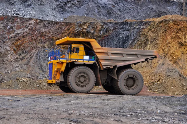 Extraction of iron ore. A mining dump truck transports iron ore along a side carrea. Special equipment works in a quarry.
