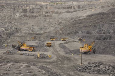 Ekipman (kazıcılar, damperli kamyonlar, sondaj kulesi) demir cevheri ocağının yolları boyunca ilerler. Taş ocağının dibine, teknolojik bir patlama için patlayıcılar yerleştirildi..