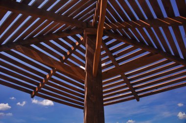 Sahilde tahta gölgelik güneş koruması. Gökyüzünün arka planına karşı