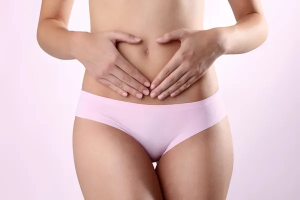 Woman's hands on stomach on white background — Stock Photo, Image