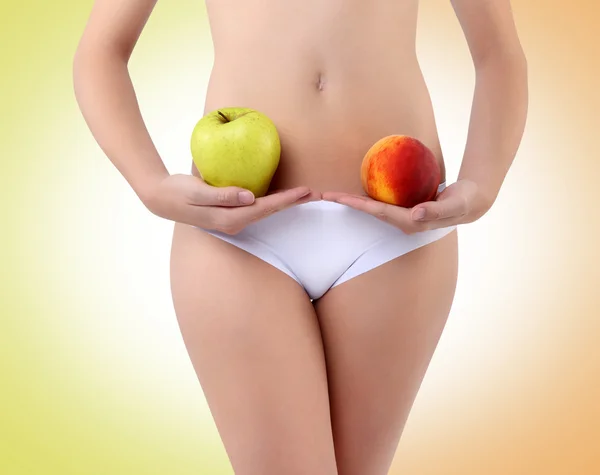 Mujer sosteniendo una manzana y melocotón con sus manos cerca del vientre —  Fotos de Stock