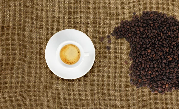 Cup of coffee with coffee beans on jute fabric — Stock Photo, Image