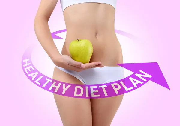 Woman holding an apple with hands near the belly — Stock Photo, Image