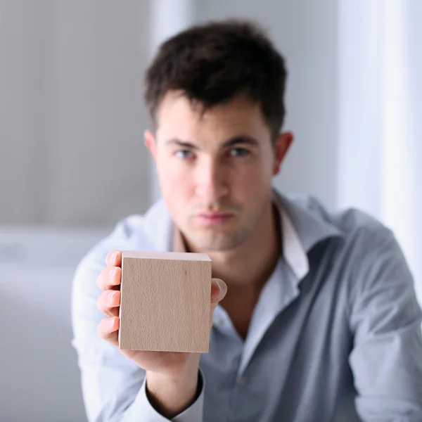 Mann zeigt einen Holzwürfel — Stockfoto