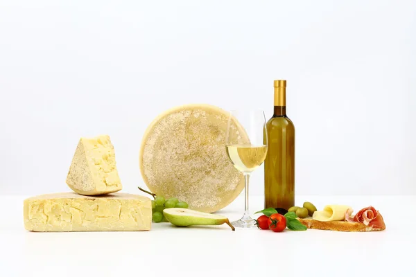Various types of cheese with wine, tomatoes, basil, olives, ham, — Stock Photo, Image