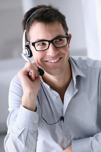 smiling man with headphones in office, call center