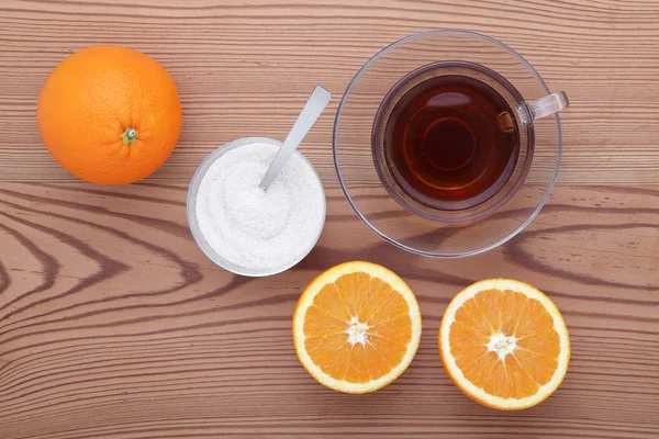 Üveg csésze tea cukor és narancs az asztalon — Stock Fotó