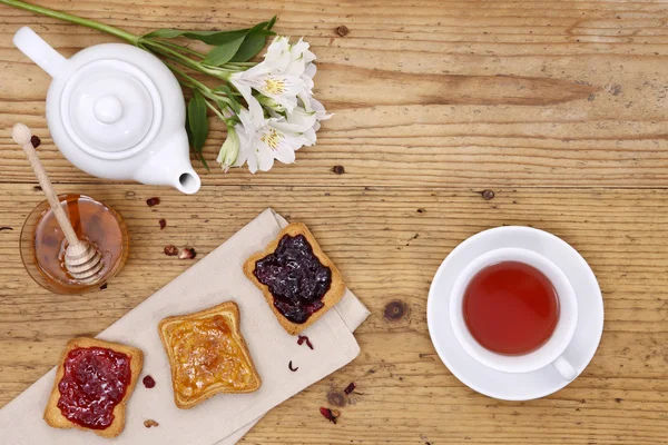 Ontbijttafel met thee, theepot, kopje thee, jam, brood en hon — Stockfoto