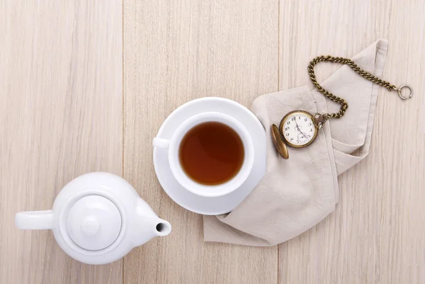 Holztisch zum Frühstück mit Tasse Tee und Uhr und Teekanne — Stockfoto