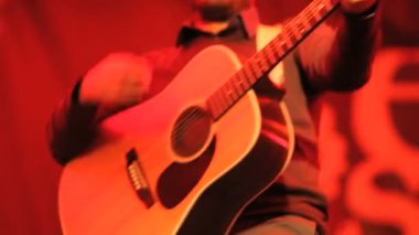 müzisyen, bir konser sırasında gitar çalıyor.