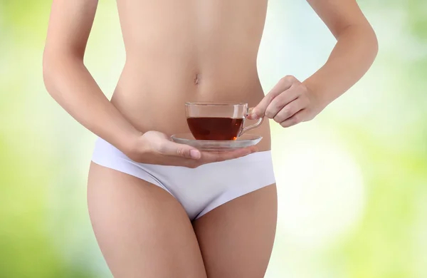 yanında yeşil bir arka plan karnına çay ile el