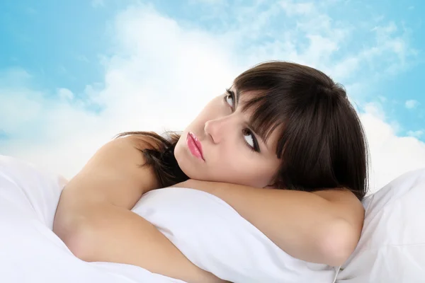 Cabeza chica durmiendo en la almohada con el cielo azul en el fondo — Foto de Stock