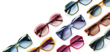 Sunglasses composition in many bright colors in transparent plastic. Top view with shadow. Trendy glasses isolated on white background. Glasses with polarized lenses. Fashionable eyewear for women.