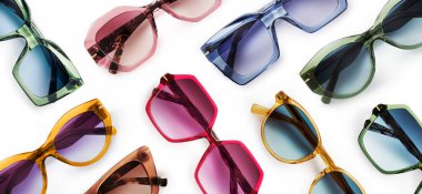 Sunglasses composition in many bright colors in transparent plastic. Top view with shadow. Trendy glasses isolated on white background. Glasses with polarized lenses. Fashionable eyewear for women.