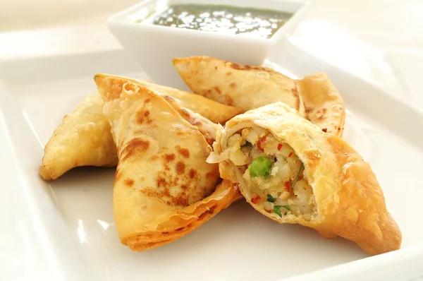 Vegetable samosas on white platter with Lal dip — Stock Photo, Image