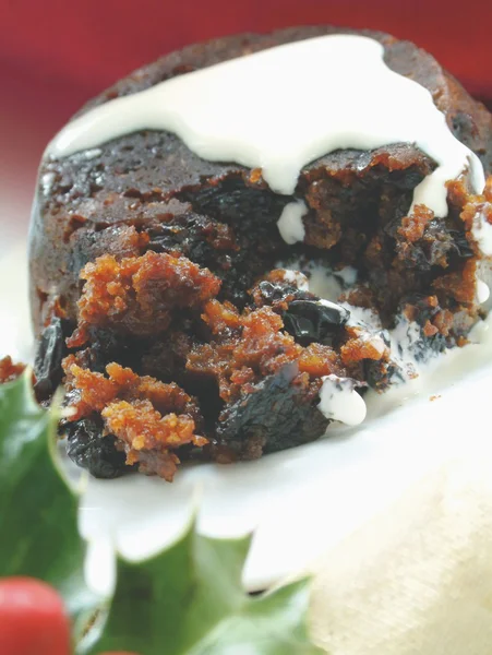 Traditional Christmas pudding with cream and holly — Stock Photo, Image