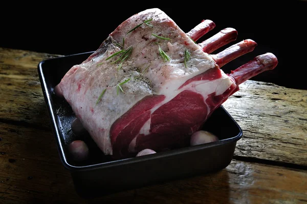 Uncooked rib of beef in roasting tin on wooden top — Stock Photo, Image