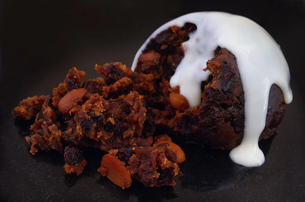 Traditionele christmas pudding met witte saus en holly — Stockfoto