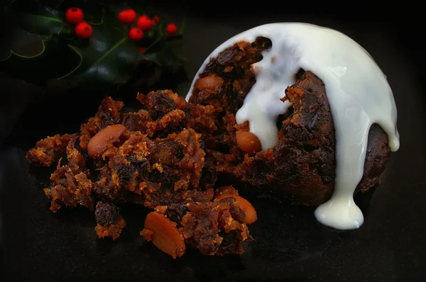 Traditioneller Weihnachtspudding mit weißer Sauce und Stechpalme — Stockfoto