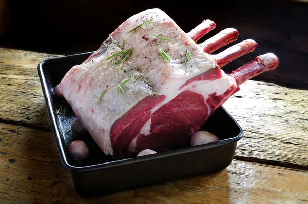 Uncooked rib of beef in roasting tin on wooden top — Stock Photo, Image