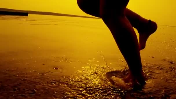 Meisje lopen in ondiep water bij zonsondergang — Stockvideo