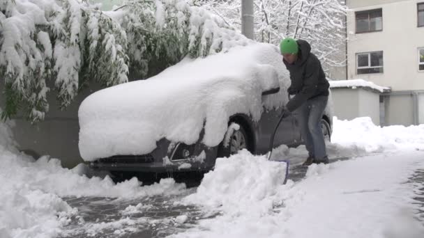 Άνθρωπος φτυαρίζει το χιόνι του αυτοκινήτου — Αρχείο Βίντεο