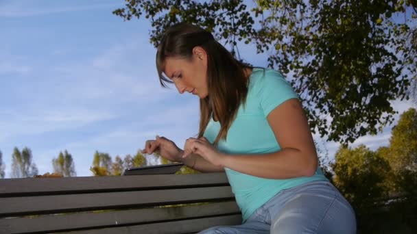 Жінка використовує цифровий планшет у парку — стокове відео