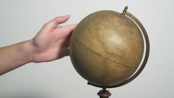L'homme tourne un globe et le pointe du doigt 