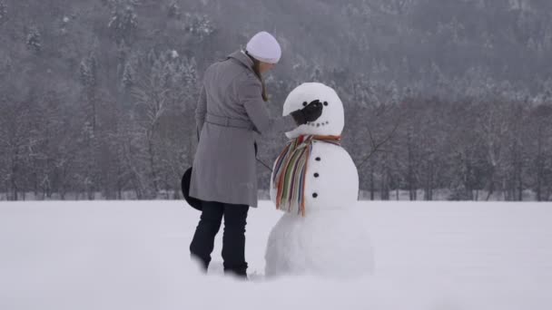 Chica construyendo un muñeco de nieve — Vídeo de stock