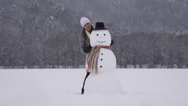 Ung kvinna bygga en snögubbe — Stockvideo