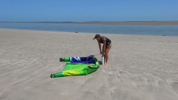 Kiteboarder hembra inflando una cometa — Vídeo de stock