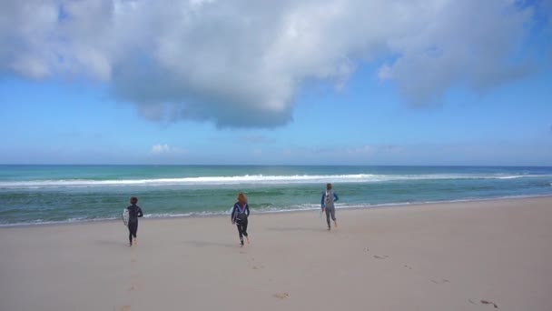 Surfers running into ocean — Stock Video