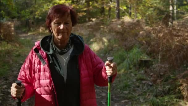 PORTRÄT: Ältere Frau hört Musik beim Trekking auf Waldweg. — Stockvideo