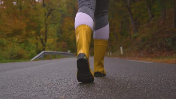 CERRAR: Mujer viajera lleva botas de goma mientras camina por una ruta forestal — Vídeo de stock