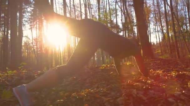 LÅNGA: Ung kvinna springer genom skogen resor och faller i hög med löv — Stockvideo