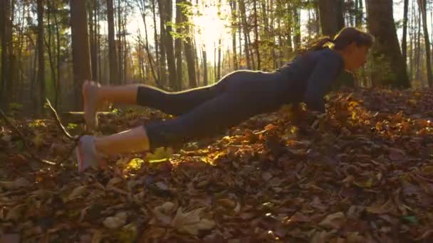 Low ANGLE:晴れた朝に森の中を走っている間にジョガーが地面につまずく — ストック動画