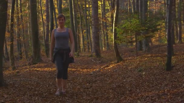 PORTRAIT Lycklig ung kvinna går längs en naturskön stig i höstfärgad skog — Stockvideo