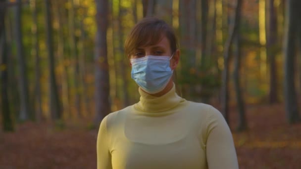 特写：戴着外科口罩的妇女在森林探险时环顾四周. — 图库视频影像